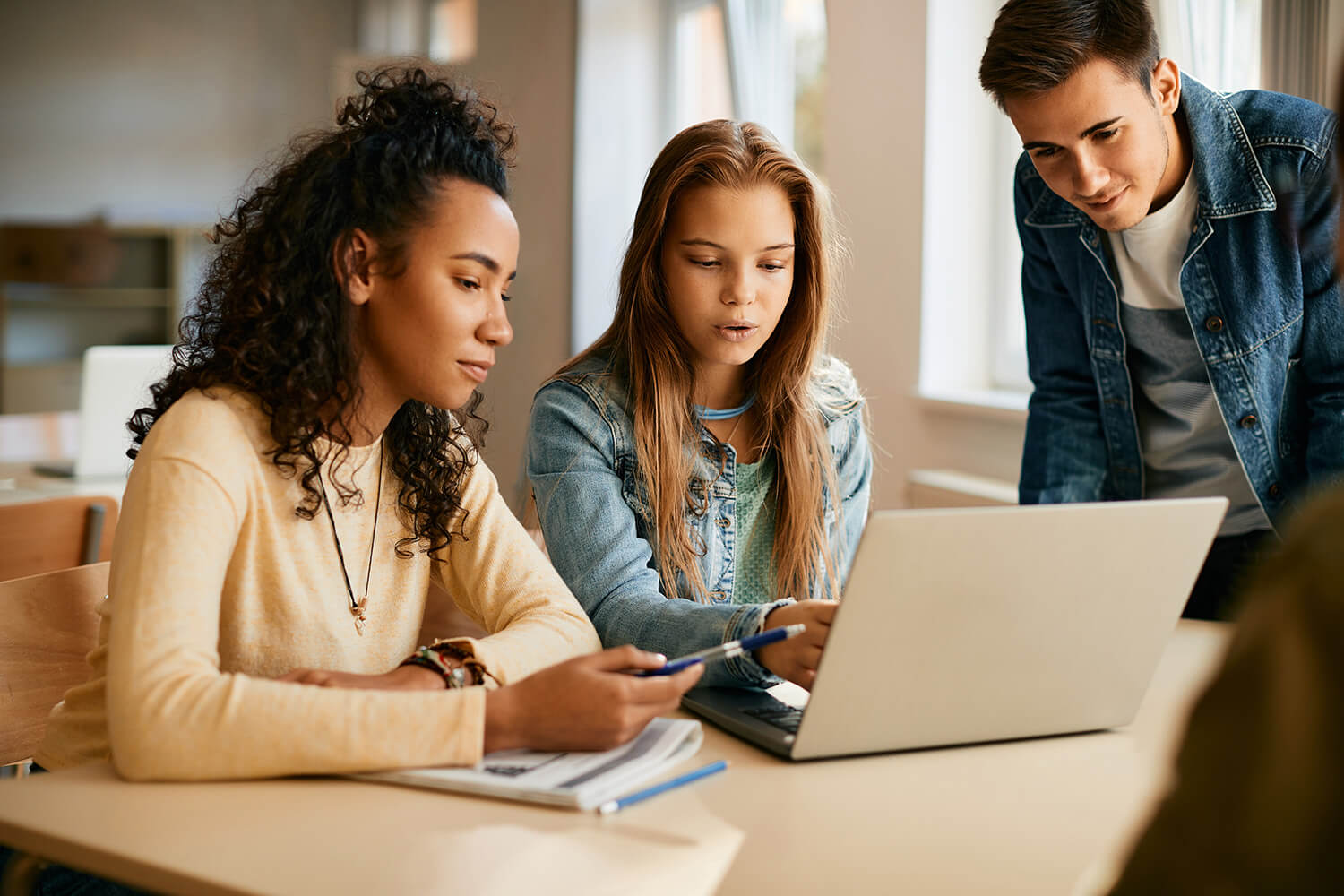 Picture of students looking at a laptop together 