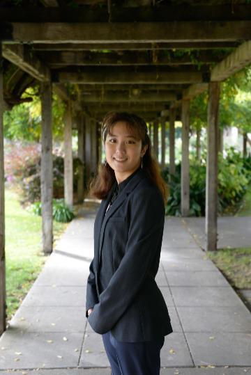 A person stands under a wooden pergola walk.