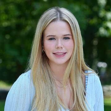 woman with blue shirt smiling outdoors