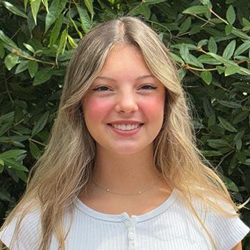 Woman in white shirt smiling outdoors