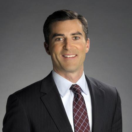 A person in a suit and tie against a gray background.