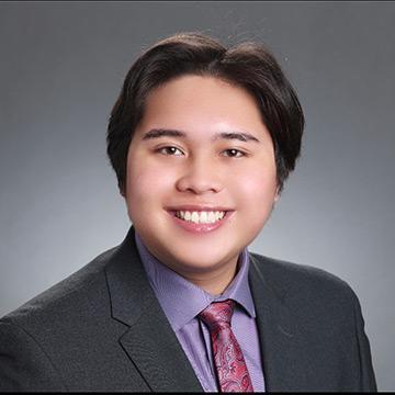 Man in suit with purple shirt and tie smiling