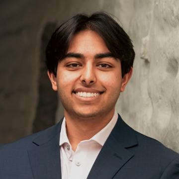 Man in dark blazer and white shirt outside smiling