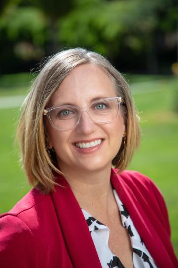 A person in a red blazer smiling outdoors.