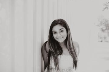 A woman smiling in front of a light-colored background.