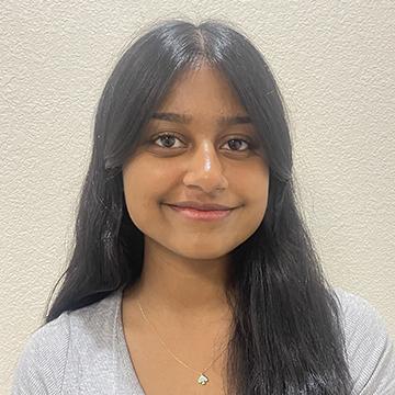 Woman in black blazer smiling outdoors