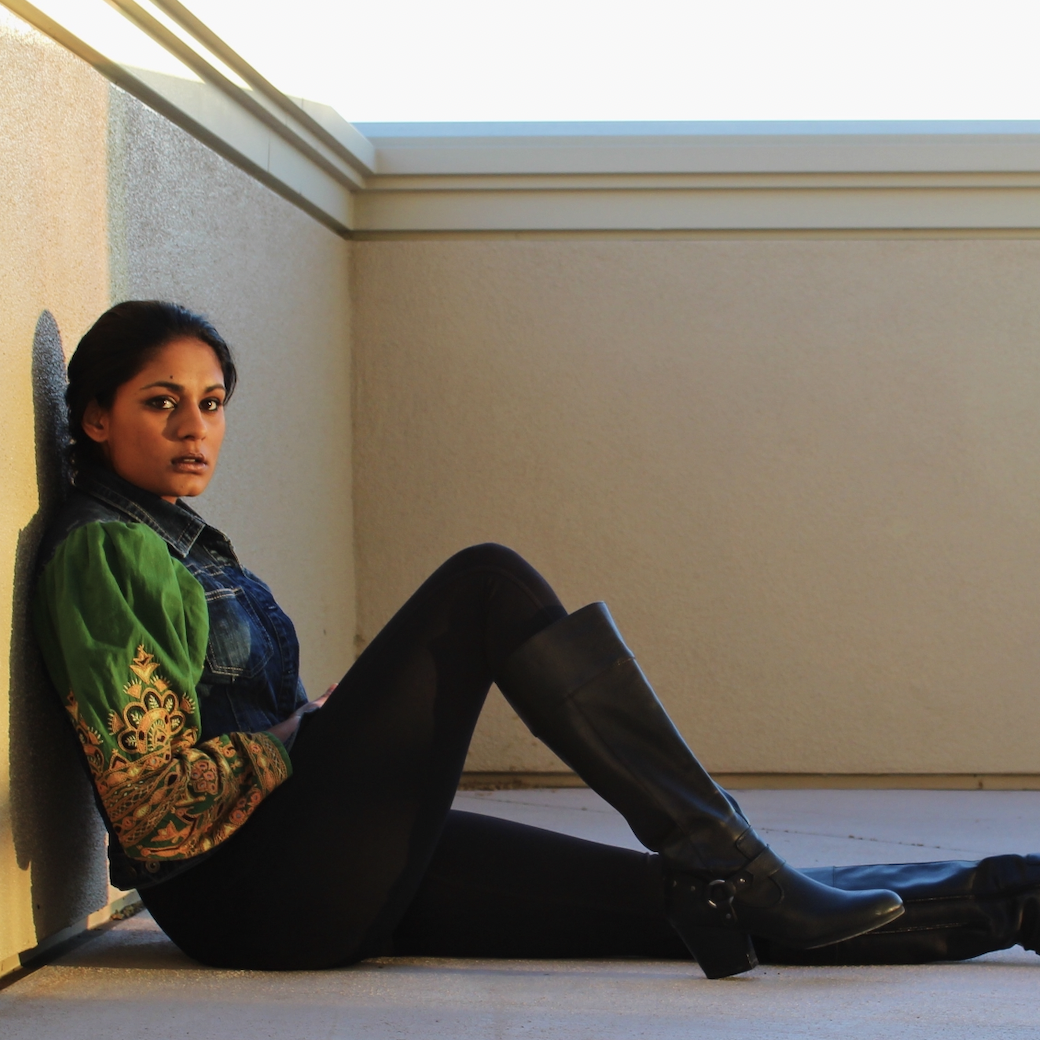 A person in a green jacket sitting by a wall, looking sideways.