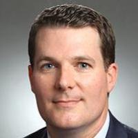 Man in a suit and tie smiling for a professional portrait.