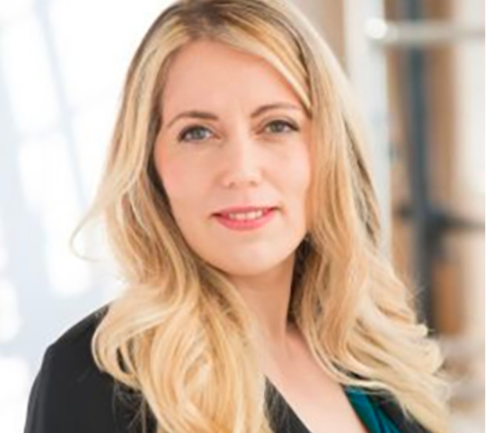A woman in professional attire posing indoors.