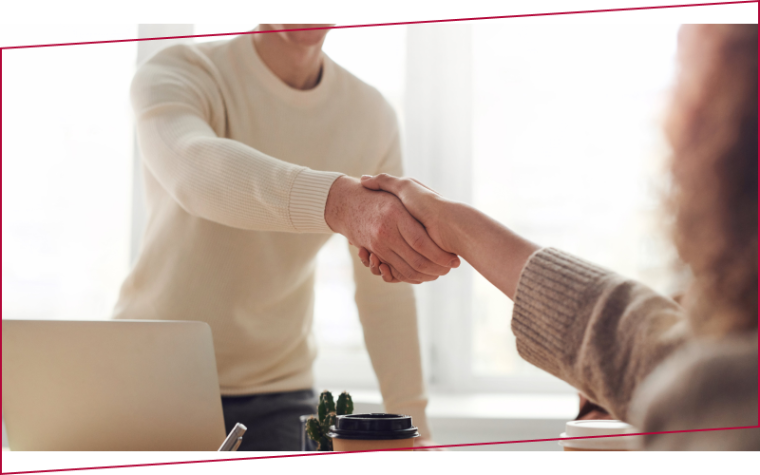 Two people shaking hands over a desk