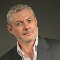 A man with a light beard and suit jacket, looking at the camera.