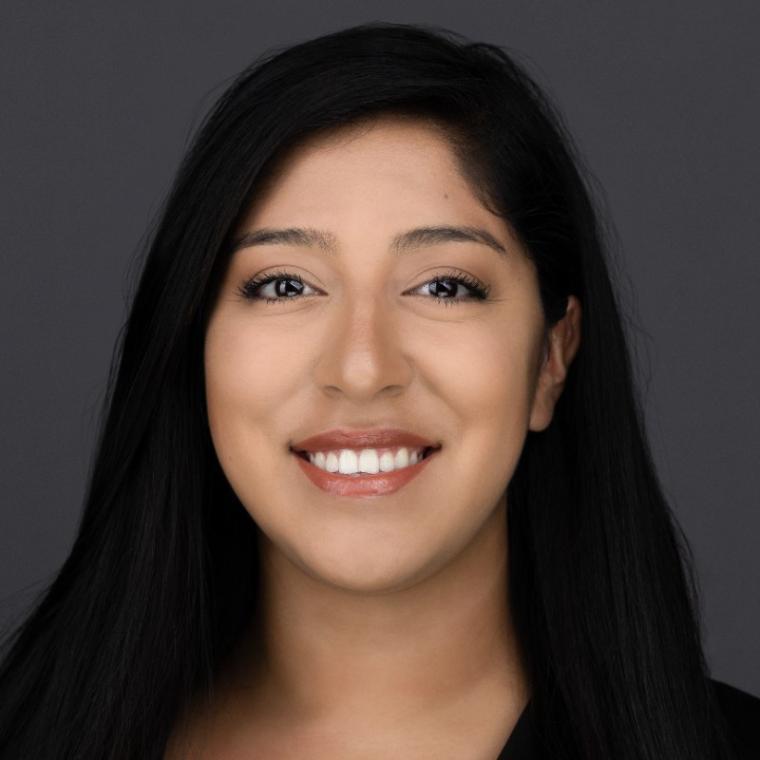 A person smiling with a grey background.