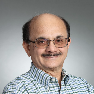 A person wearing glasses and a checkered shirt, smiling at the camera.