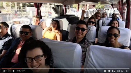 Students sitting on a bus, smiling for the photo