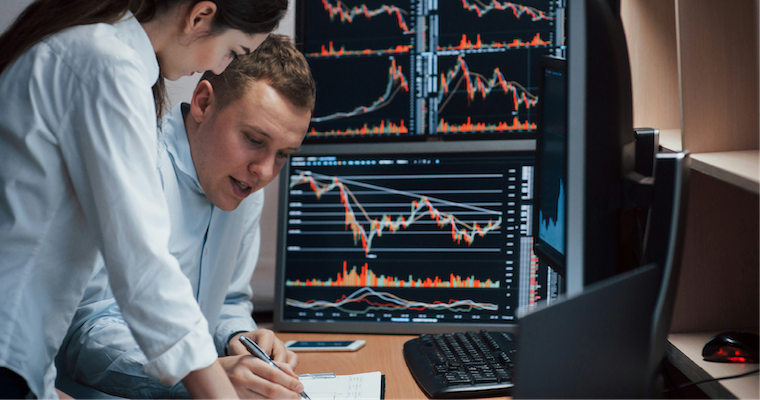 Business professionals analyzing data with multiple monitors full of charts