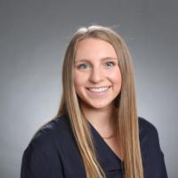 A person smiling against a gray background.