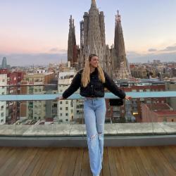 A person posing on a rooftop with a scenic city view.