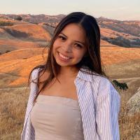 A person smiling with hills in the background at sunset.