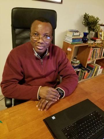 A person seated at a desk, smiling.