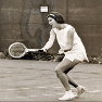 A female tennis player prepares to hit a forehand in a vintage photo.