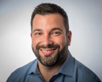A man smiling in a blue shirt.
