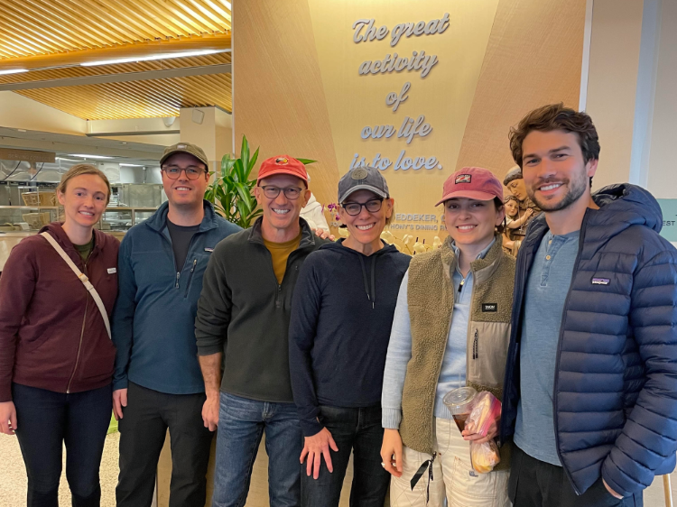A group of smiling people in front of a sign that says 