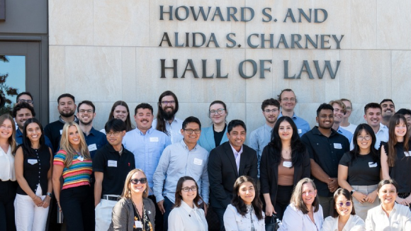 A group of smiling people in front of a Santa Clara University building labeled