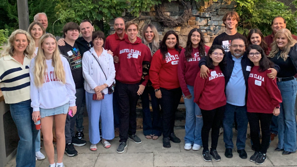 A group of smiling people, many of them in Santa Clara University-branded clothing.