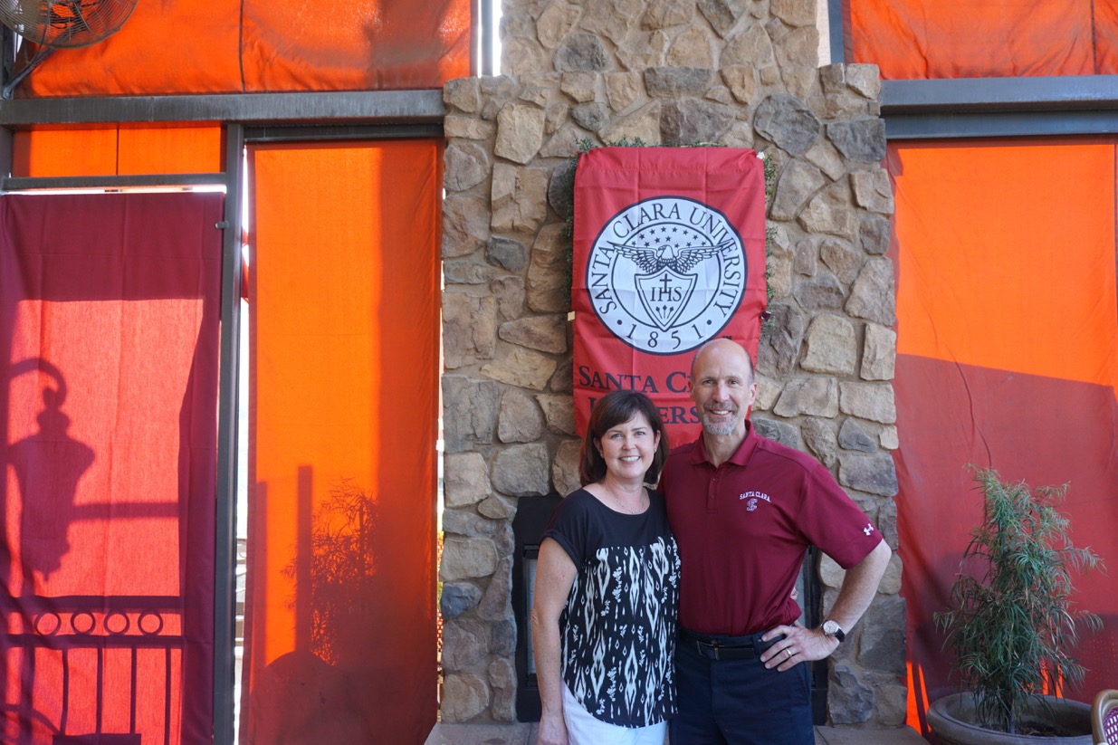 Two people standing in front of a sign that reads 'Dog House Grill.'