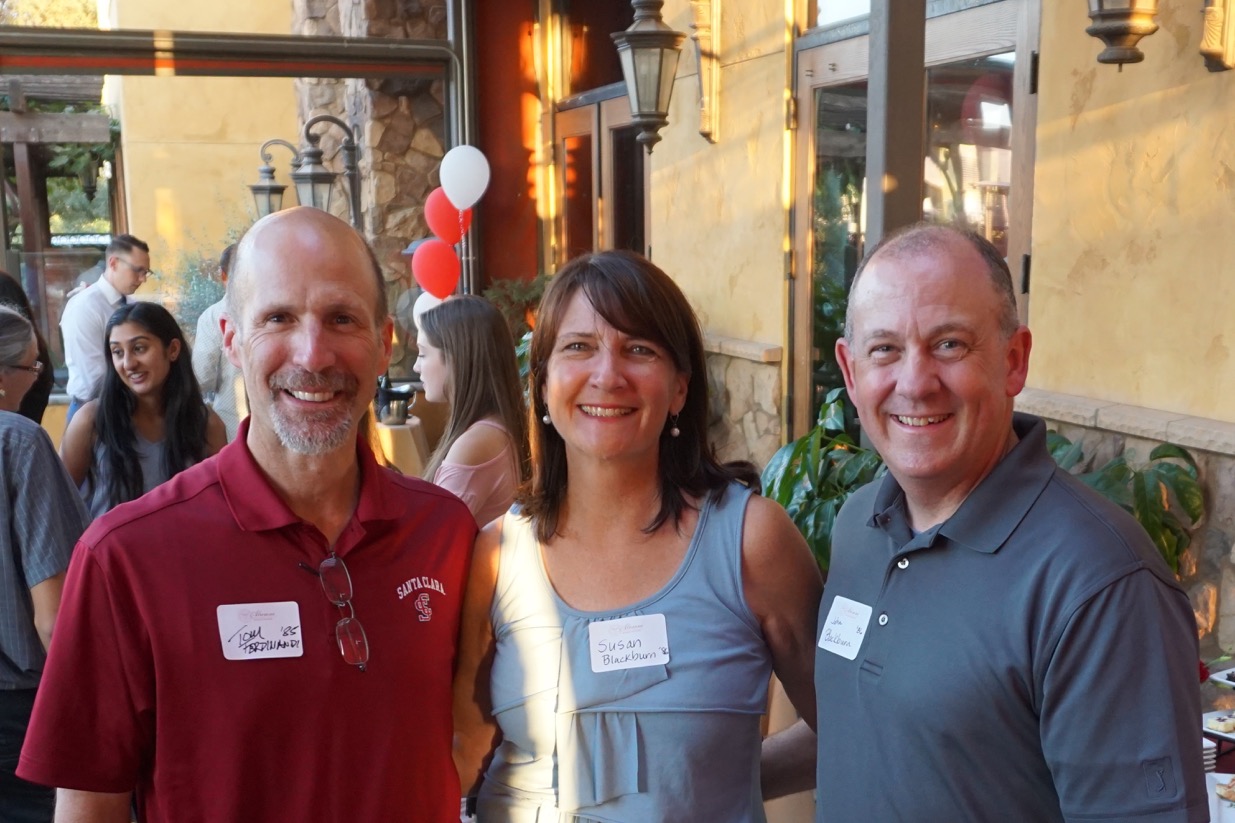 Three people posing together at an event, wearing nametags.