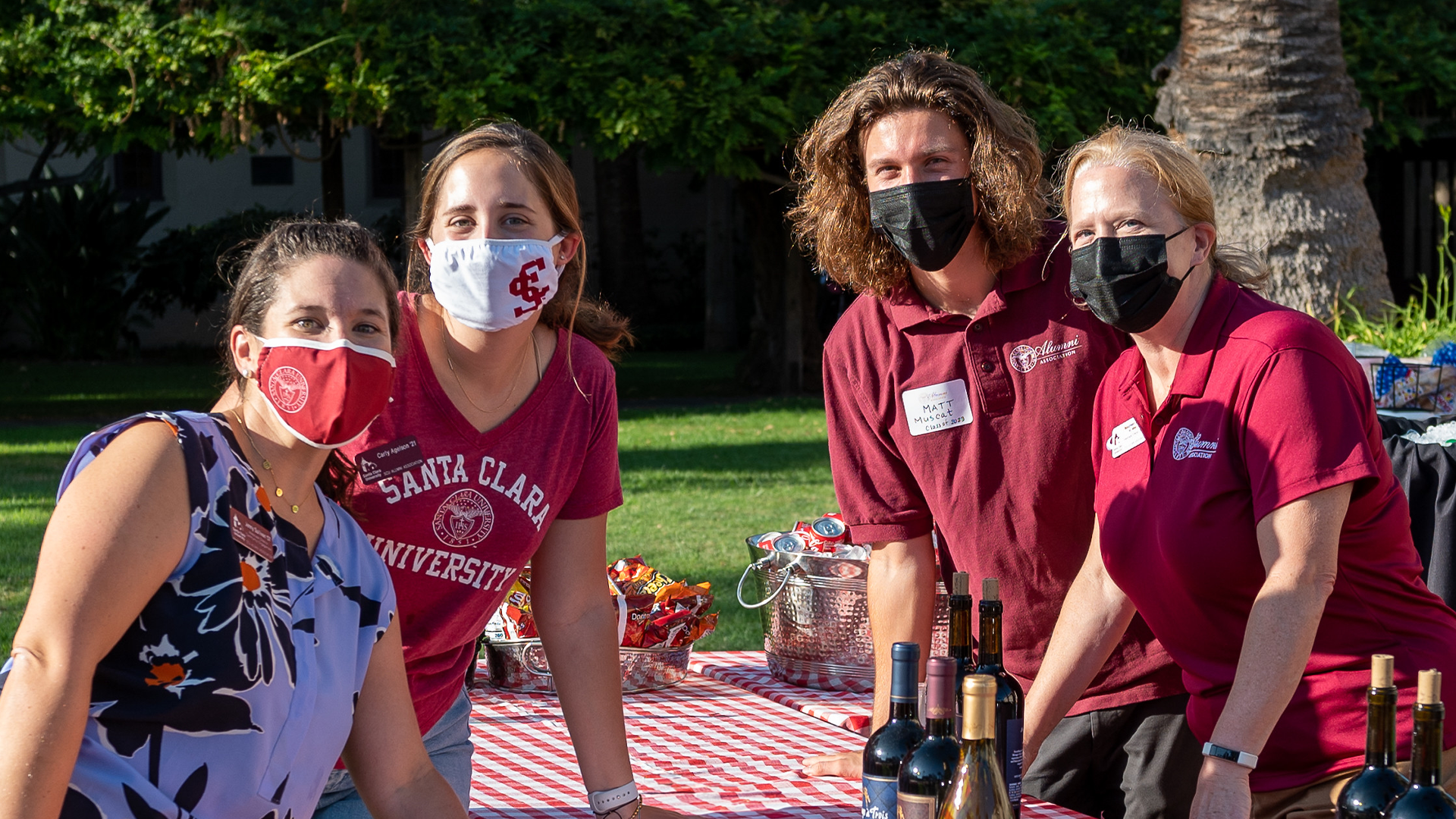 Four alumni staffers wearing face masks and grouped around a table