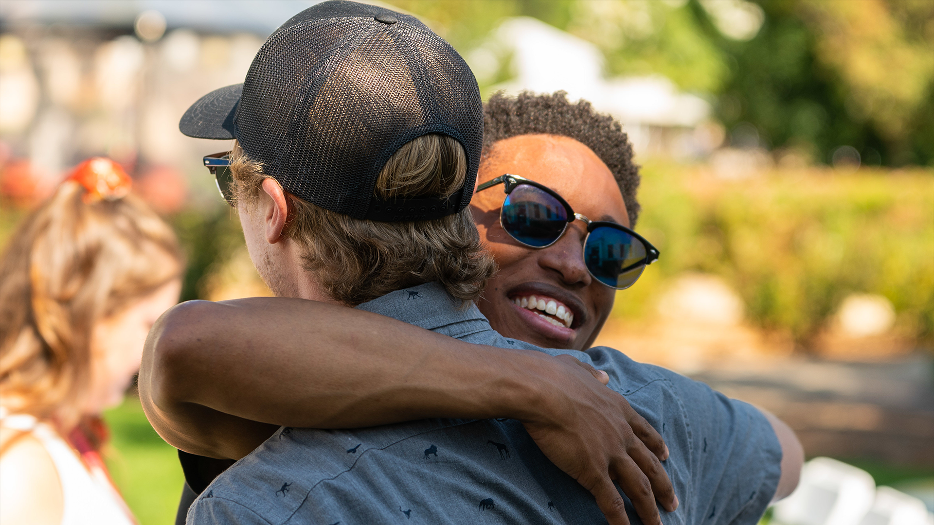 Two young alumni hugging each other