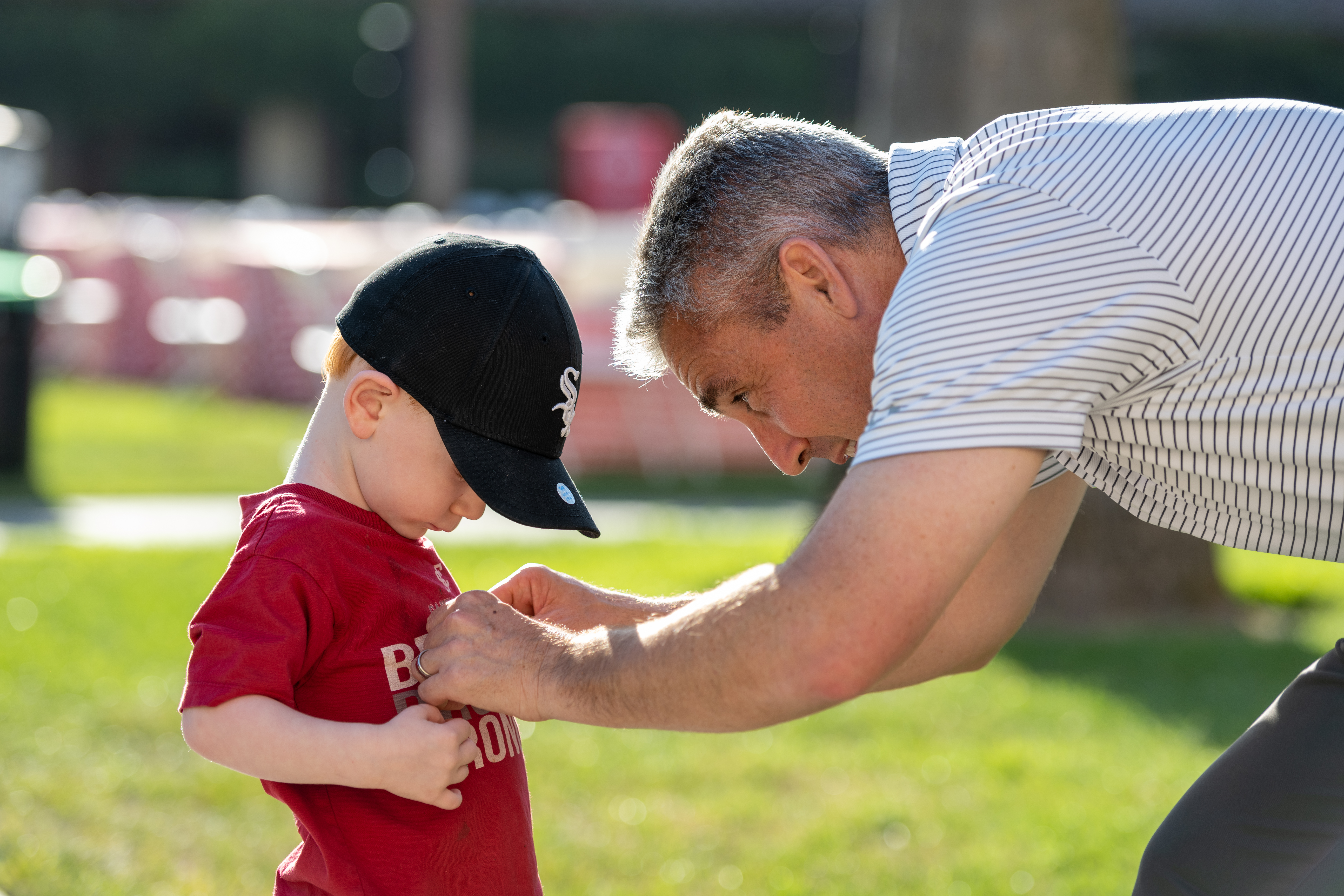 An adult assisting a child with a tag at a BBQ event.