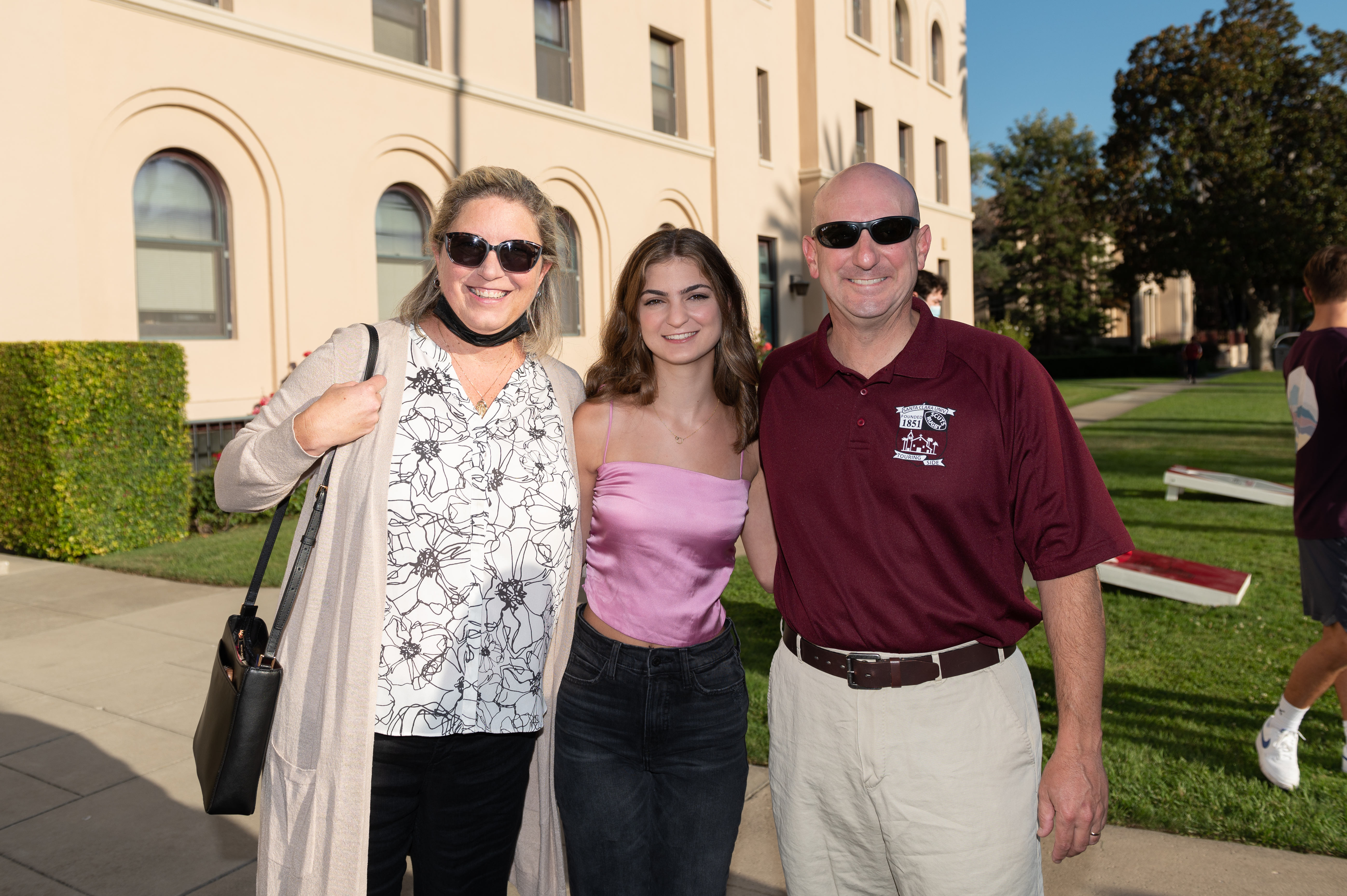 Three people posing outside a building at Legacy BBQ event.
