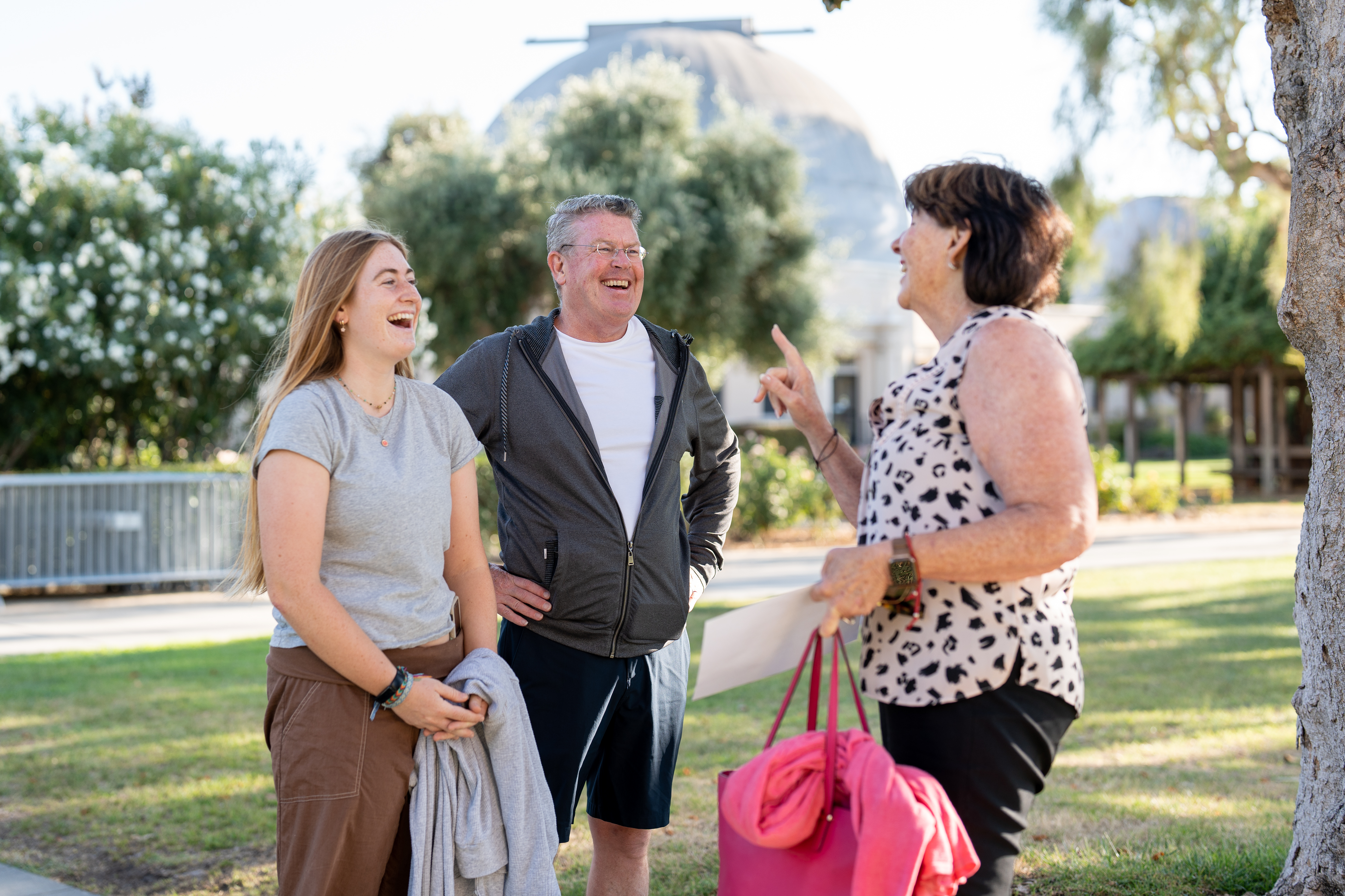 Three people conversing outdoors at Legacy BBQ Alumni Family Scholarship event.