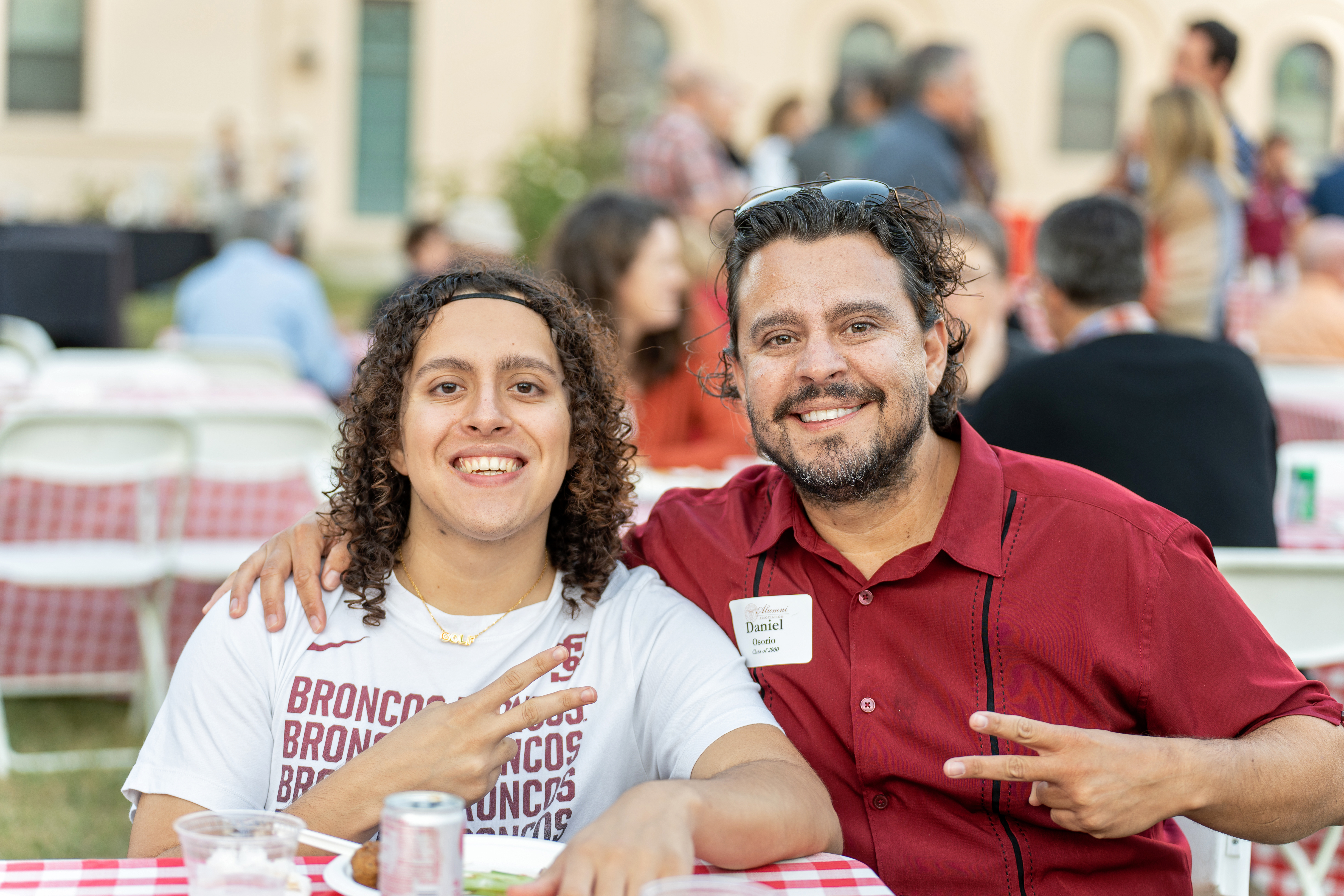 Two people smiling at a barbecue event, wearing name badges.