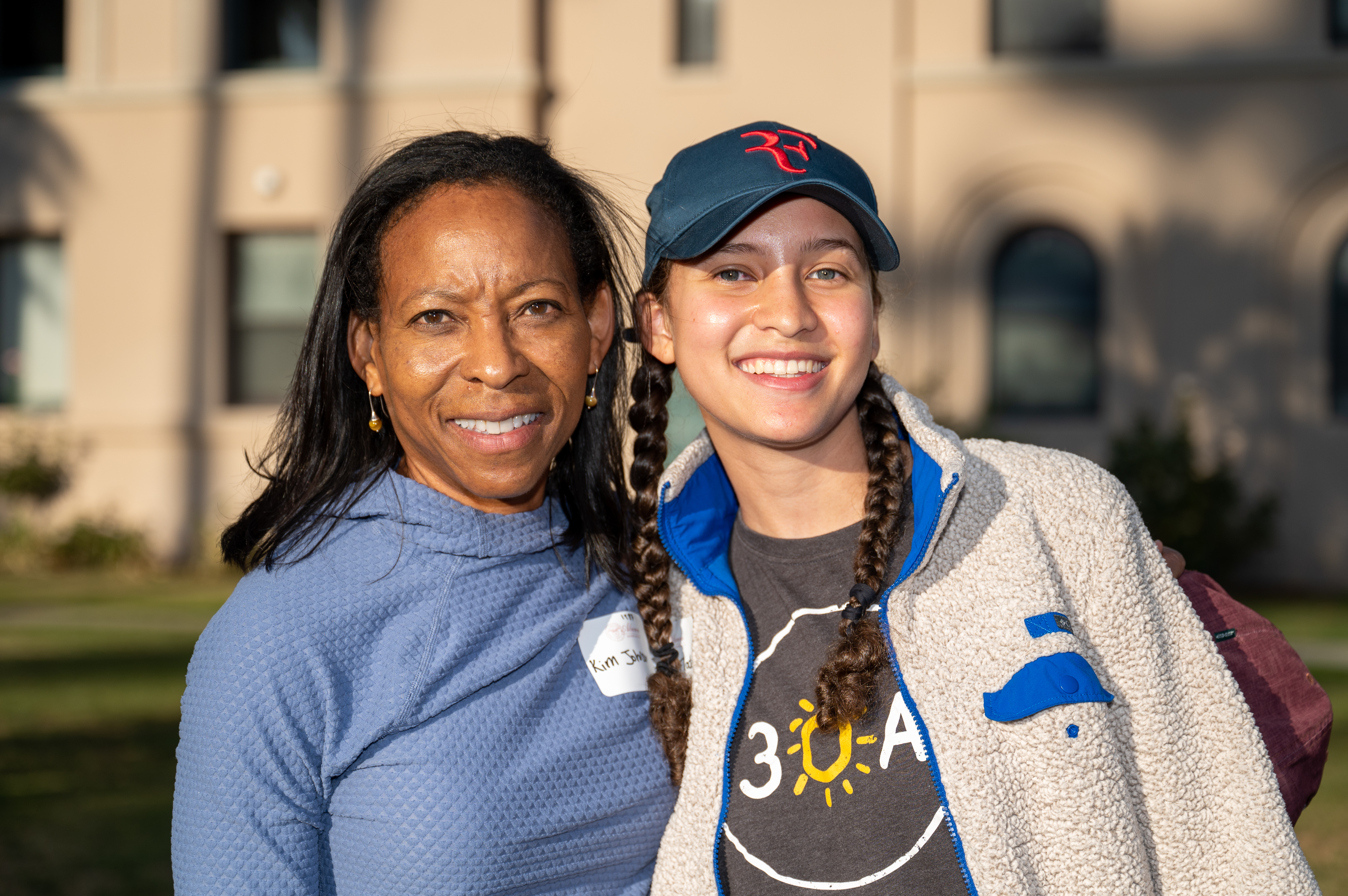 Two people smiling outdoors at Legacy BBQ Alumni Family Scholarship event.