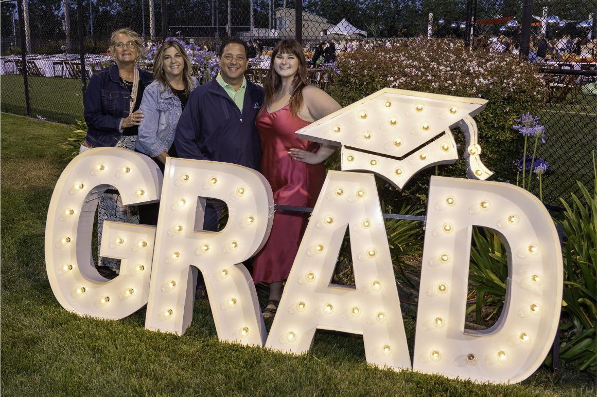 A family posing with large, light-up letters spelling out 