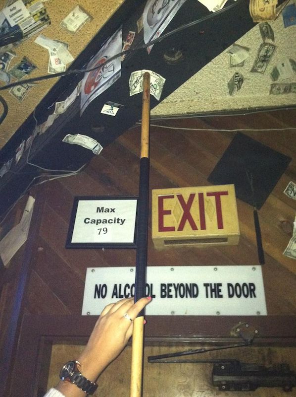 Climbing wall exit sign with a hand on a hold.