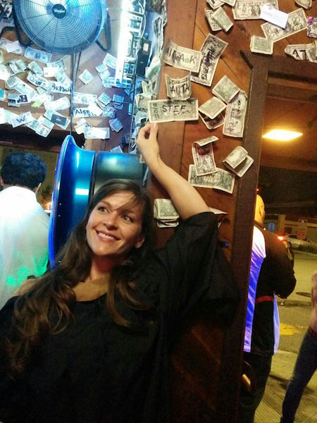 A person smiling in front of a decorated wall.