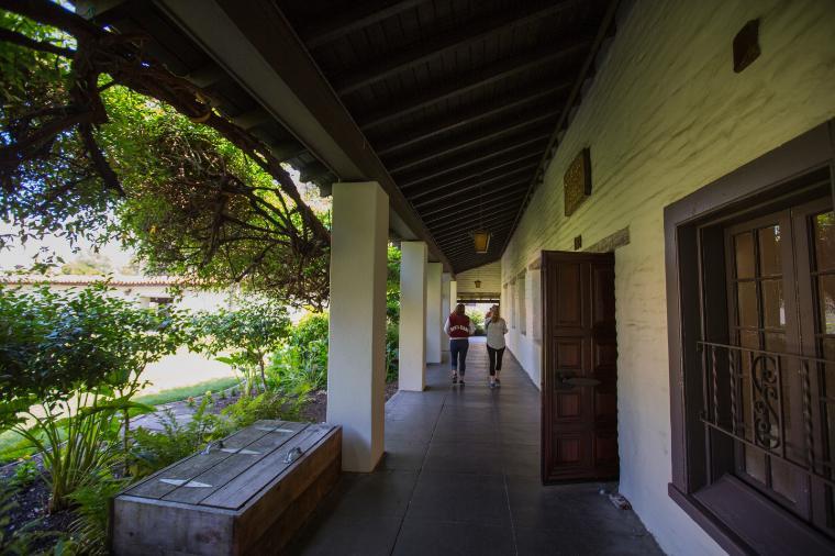 A covered adobe portico with columns and a garden view.