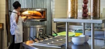 An executive chef preparing and presenting food in a dining service setting.