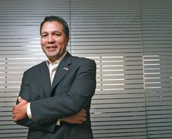 A person in a suit stands with arms crossed, smiling.