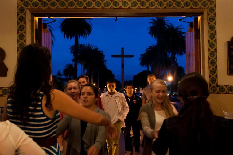 A group of people entering a building at dusk.