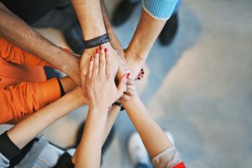 A group of hands stacked together in a gesture of teamwork.