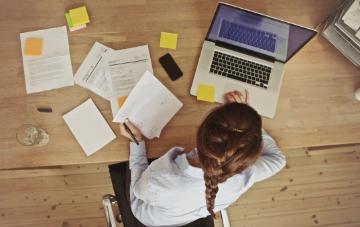 Overhead view of person working at desk with laptop and documents.