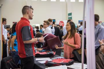 People interacting at a busy career fair booth.
