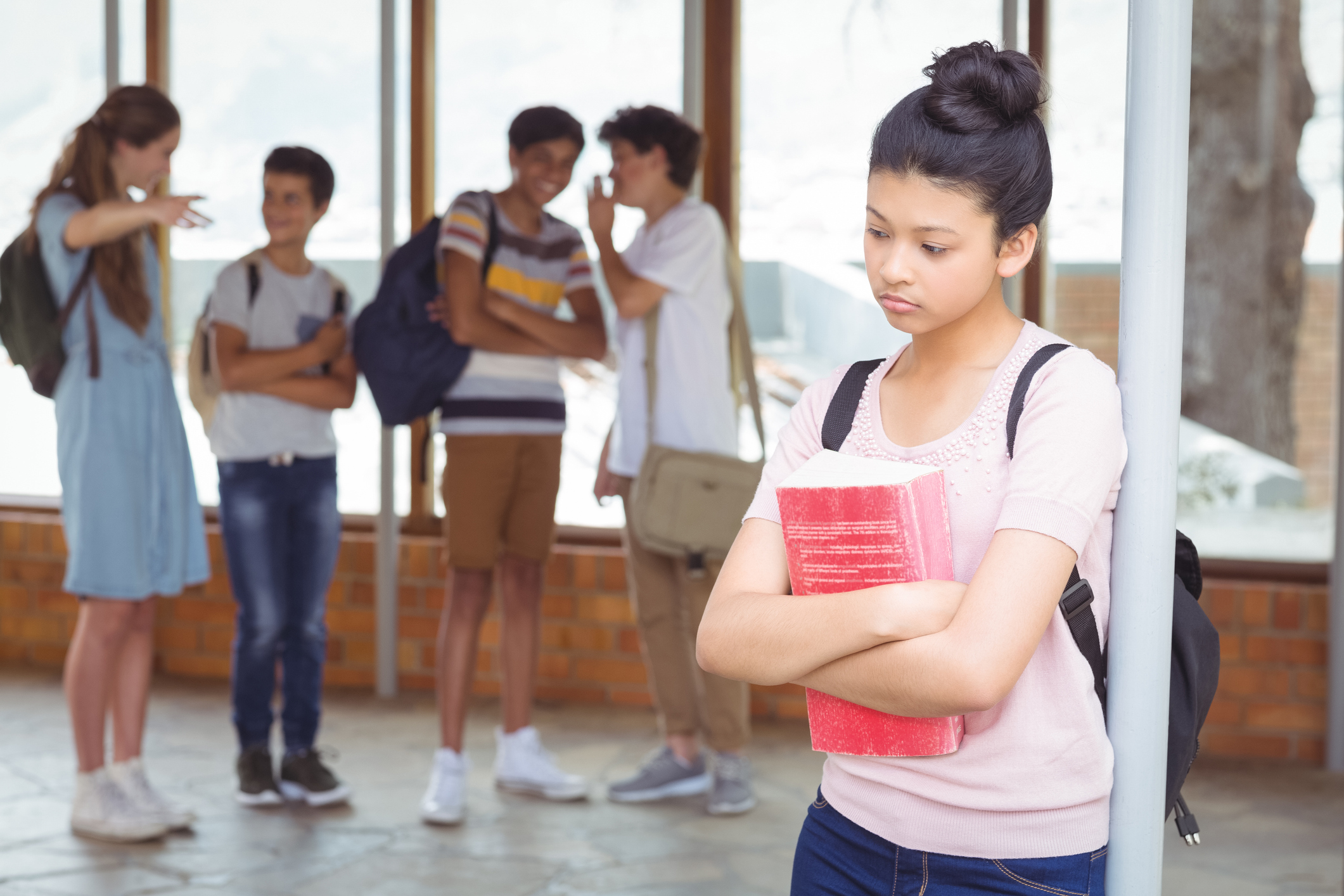 A group of students bullying a sad girl in a school hallway.