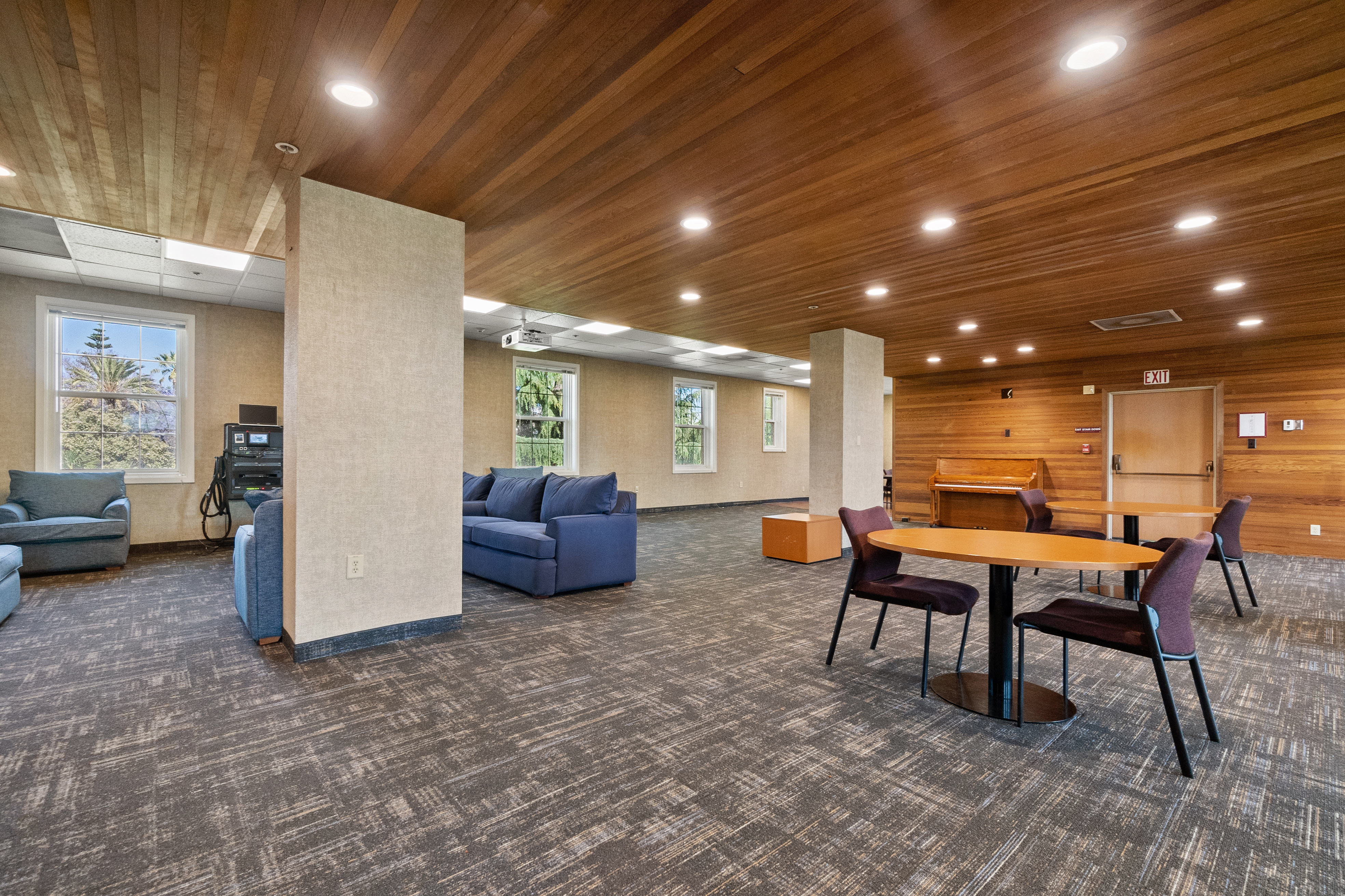 Modern lounge area with comfortable seating, wooden ceiling, and overhead lighting.