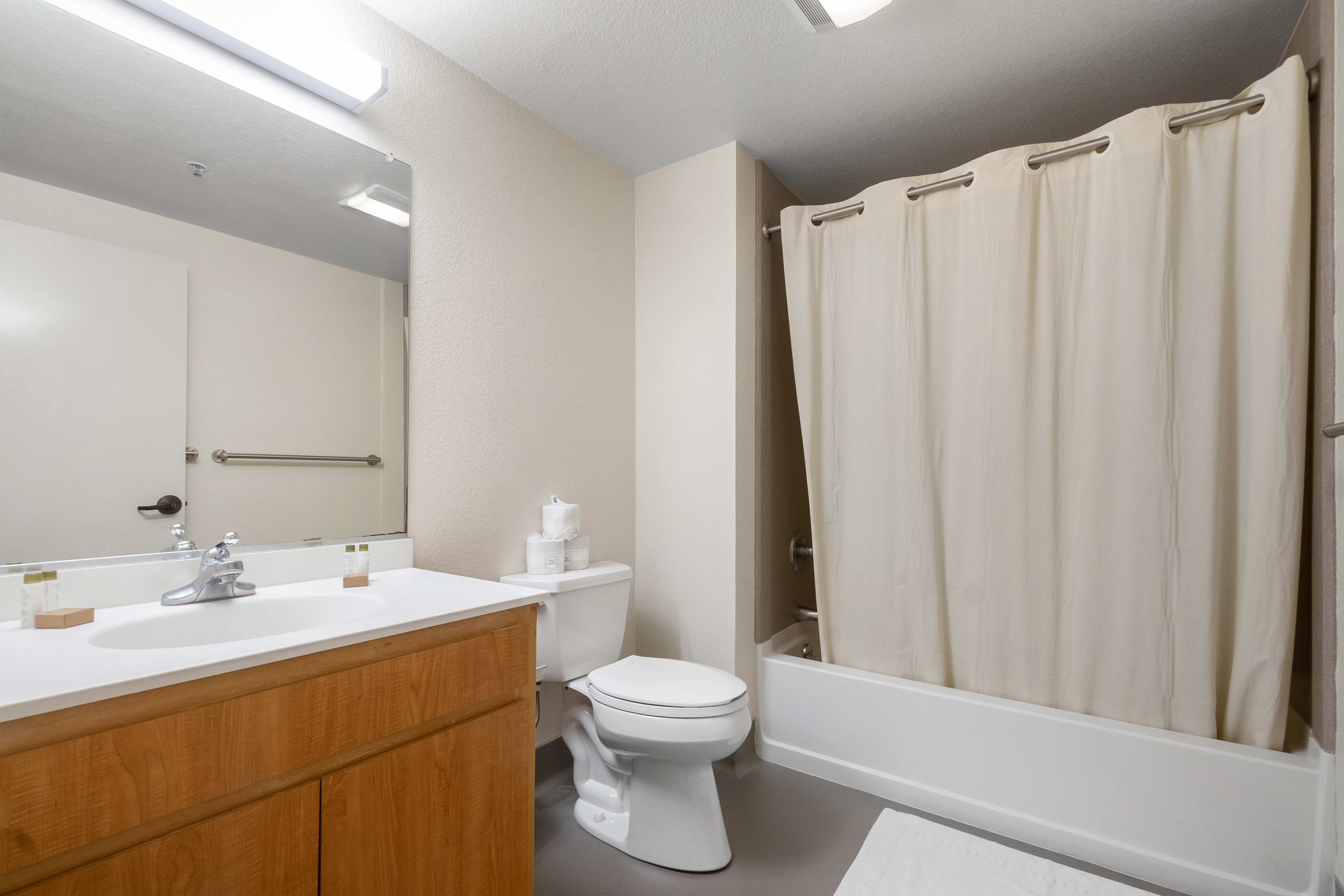 A clean white bathroom with a shower, vanity, and toilet.